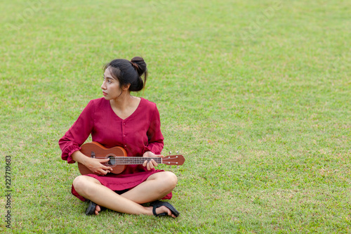 Beautiful young asian woman is playing ukulee photo