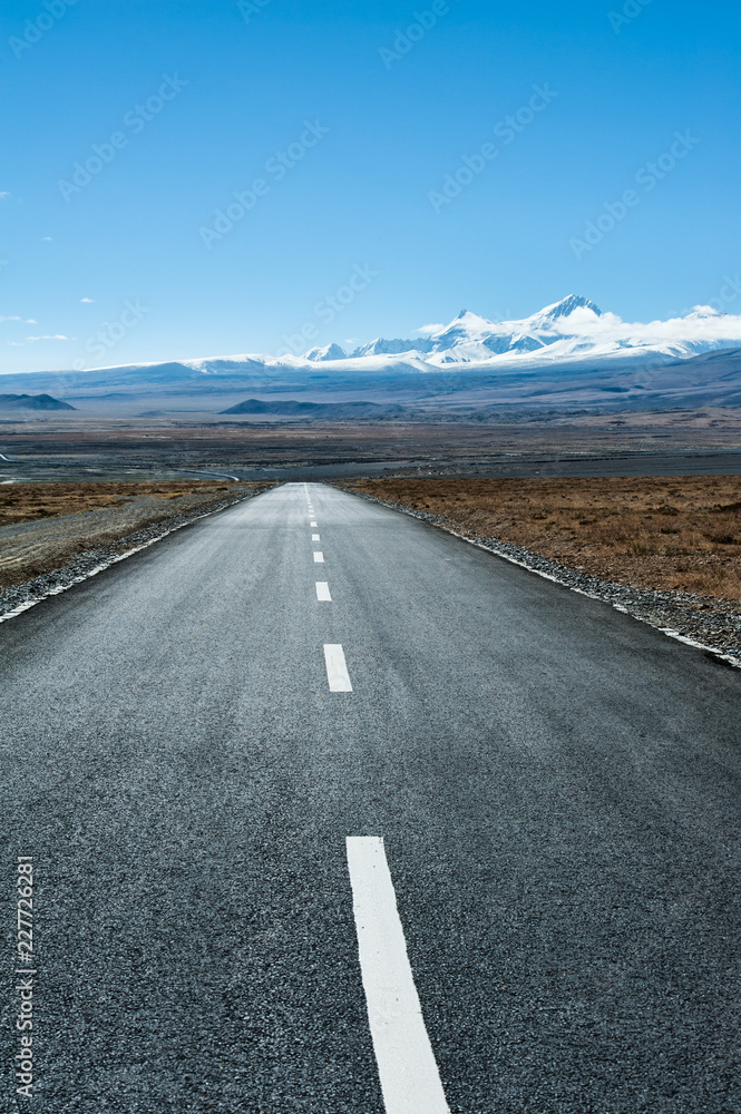 Naklejka premium Road leading toward snow mountain peak in the distance