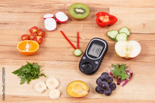 Glucometer with fruits and vegetables showing time of 23 hours 55 minutes, healthy eating for diabetics in new year concept