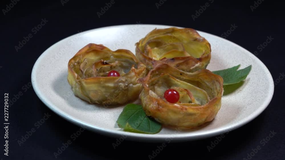 Oven-baked potato in the shape of a flower served on a plate, rotates, close up, black background Oven-baked potato in the shape of a flower served on a plate, rotates, close up, black background