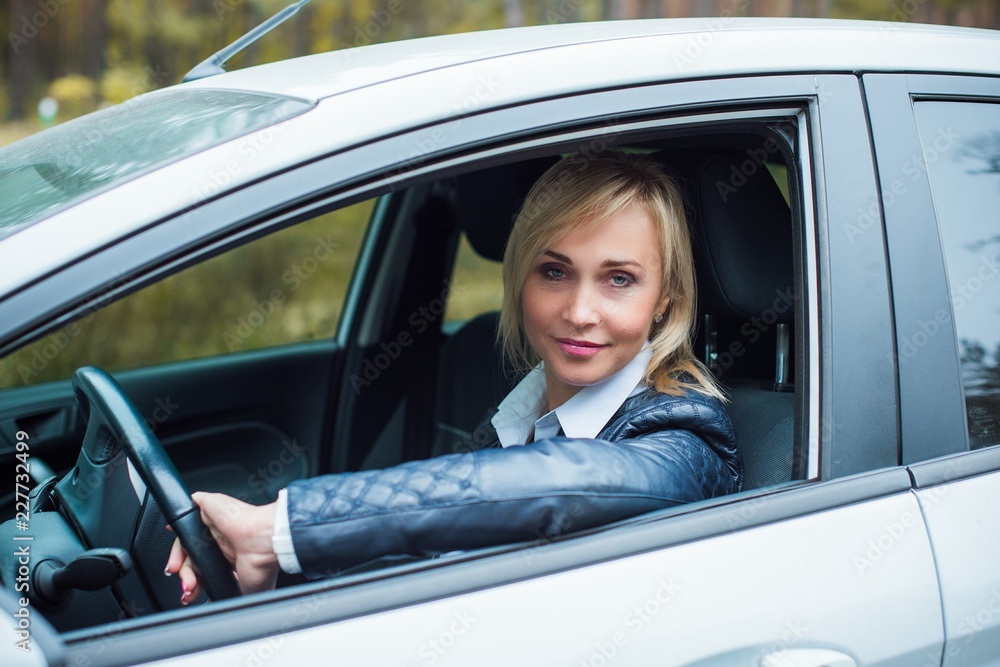 European mature elegant woman and car, lady driving automobile, outdoors portrait. Middle age woman driving on road, trip on beautiful autumn day. Concept of women and auto European mature elegant woman and car, lady driving automobile, outdoors portrait. Middle age woman driving on road, trip on beautiful autumn day. Concept of women and auto