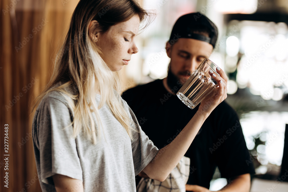 Two young friendly barista, wearing casual style,are stading next to each other and look at the glass in a cozy coffee shop. Two young friendly barista, wearing casual style,are stading next to each other and look at the glass in a cozy coffee shop.