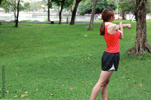 Fitness young Asian woman stretching her hands before run in park. Workout and exercise concept.