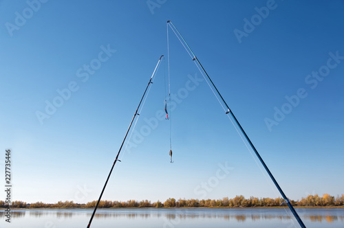 Obraz na płótnie Two spinning rods on the background of the bank of the autumn river w salonie