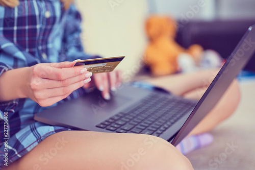 Young woman hands holding credit card and working with laptop at home.