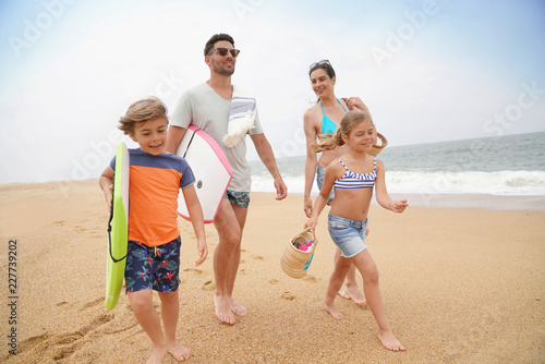 Family of 4 walking on sandy beach, ocean view