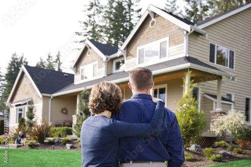 happy couple in front of house in front of new house