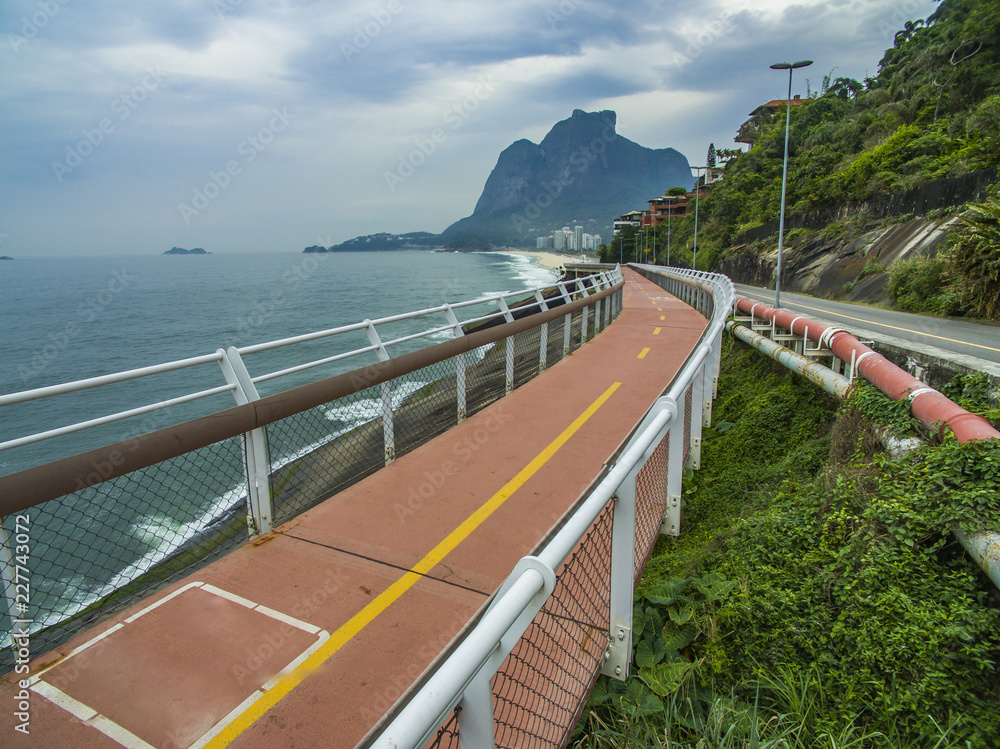 Obraz premium Highway by the sea. Wonderful road and bike path. Bicycle and road track and next to the blue sea in the city of Rio de Janeiro. Tim Maia bike path on Niemeyer Avenue, Rio de Janeiro, Brazil.