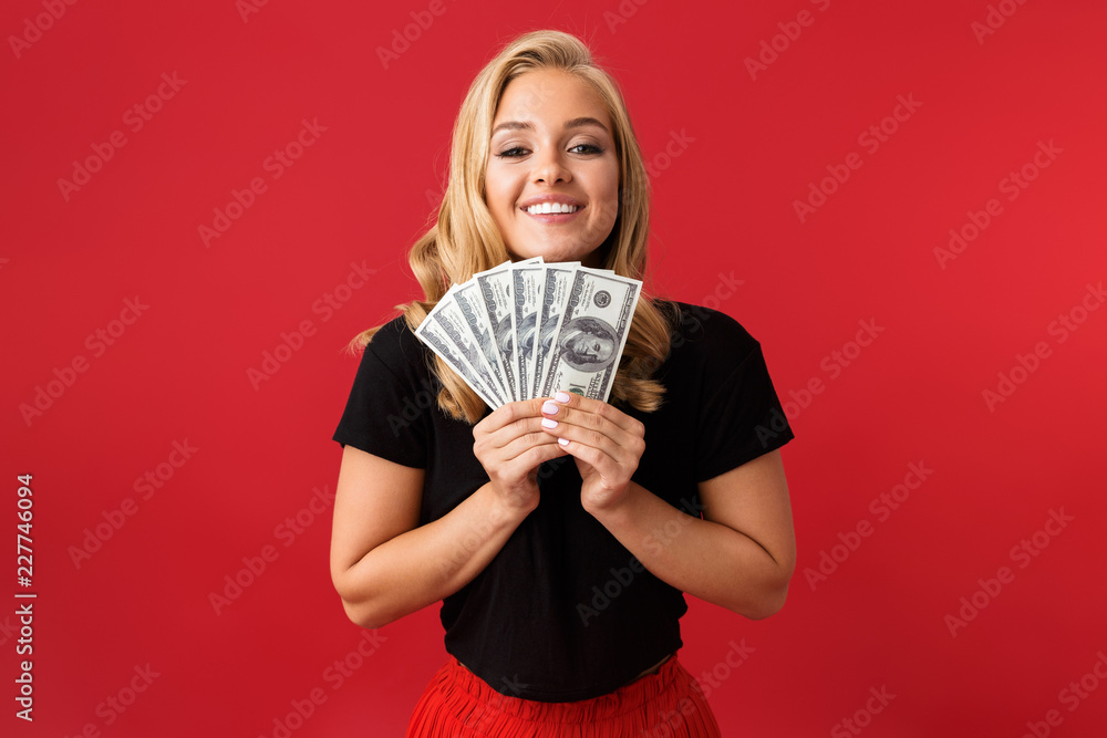 Excited woman holding money isolated over red background. Excited woman holding money isolated over red background.
