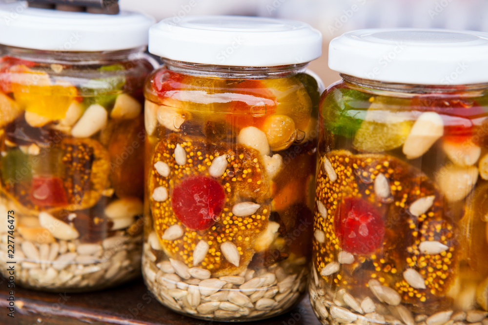 Healthy combination of natural honey with various nuts and dried fruits in jars Healthy combination of natural honey with various nuts and dried fruits in jars