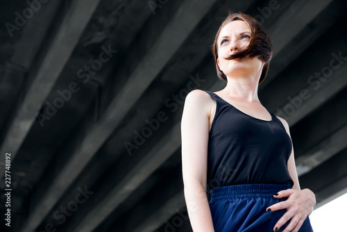 young girl posing under the bridge, dressed in black, modern architecture