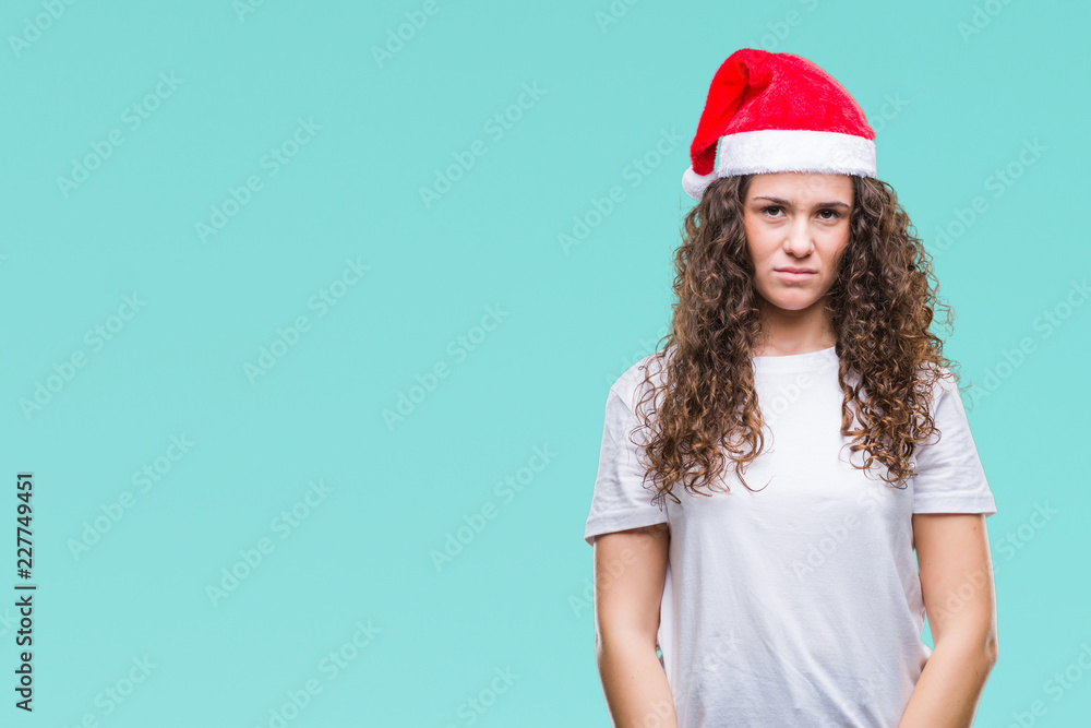 Young brunette girl wearing christmas hat over isolated background with serious expression on face. Simple and natural looking at the camera. Young brunette girl wearing christmas hat over isolated background with serious expression on face. Simple and natural looking at the camera.