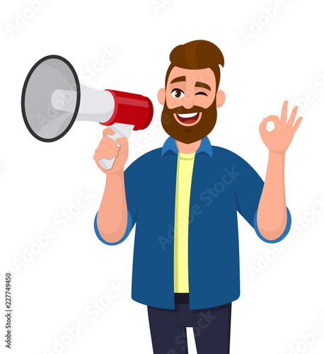 Man holding a megaphone/loudspeaker, winking eye and showing/gesturing OK/okay sign. Megaphone concept illustration in vector cartoon style.