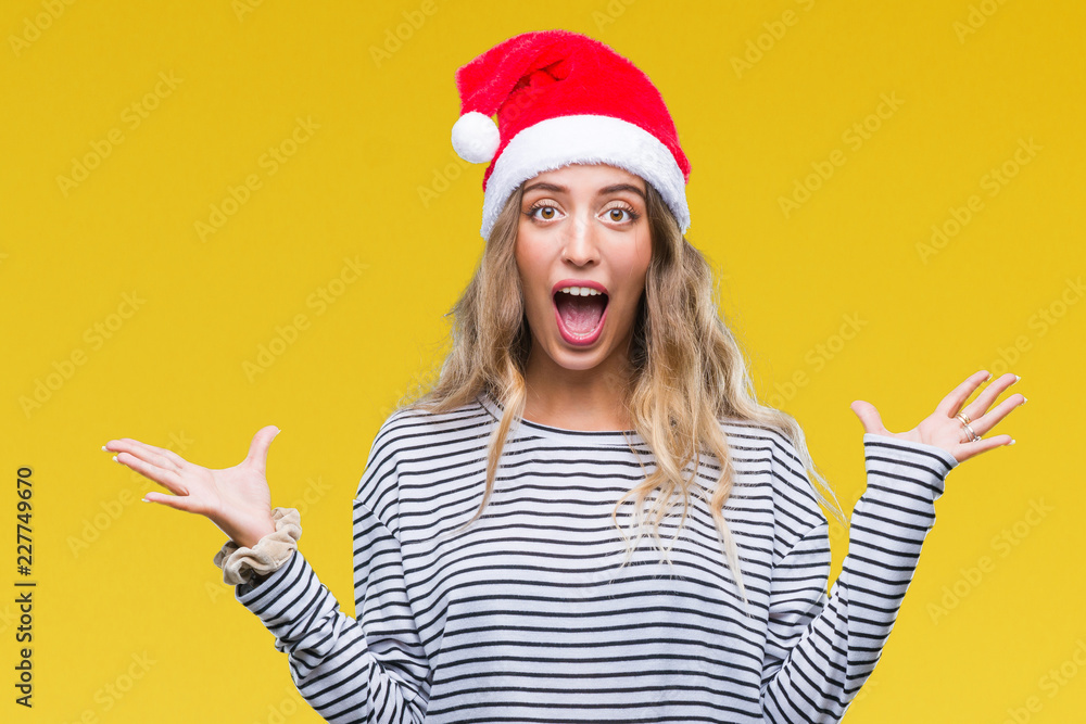 Beautiful young blonde woman wearing christmas hat over isolated background celebrating crazy and amazed for success with arms raised and open eyes screaming excited. Winner concept Beautiful young blonde woman wearing christmas hat over isolated background celebrating crazy and amazed for success with arms raised and open eyes screaming excited. Winner concept