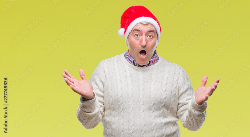 Fototapeta premium Handsome senior man wearing christmas hat over isolated background celebrating crazy and amazed for success with arms raised and open eyes screaming excited. Winner concept