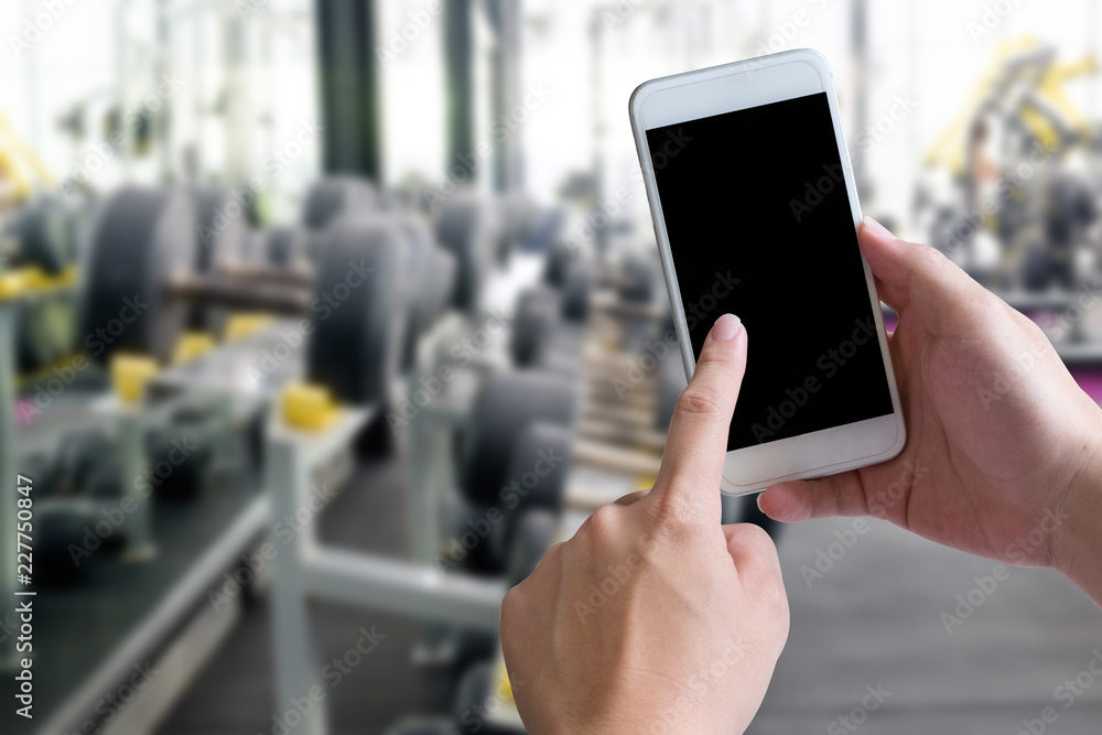 Hands using smartphone in fitness sport gym with mockup mobile for present.