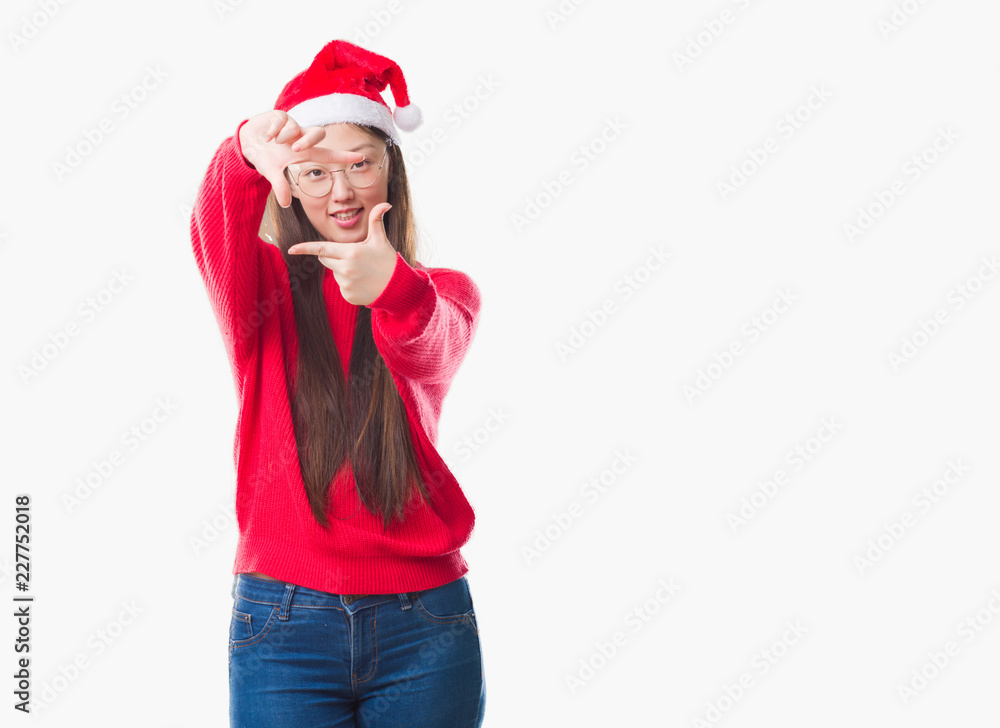 Young Chinese woman over isolated background wearing christmas hat smiling making frame with hands and fingers with happy face. Creativity and photography concept. Young Chinese woman over isolated background wearing christmas hat smiling making frame with hands and fingers with happy face. Creativity and photography concept.