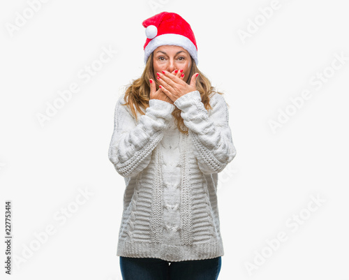 Middle age senior hispanic woman wearing christmas hat over isolated background shocked covering mouth with hands for mistake. Secret concept.