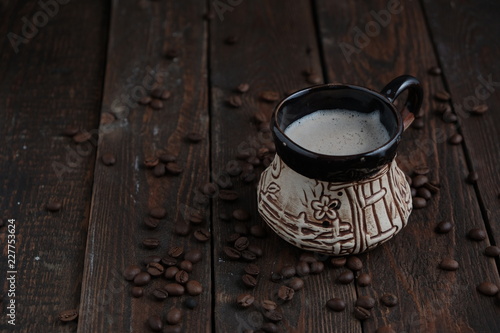 Coffee cup with beans on dark wood background