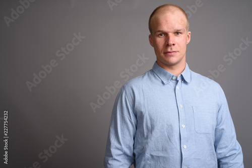 Bald businessman wearing blue shirt against gray background