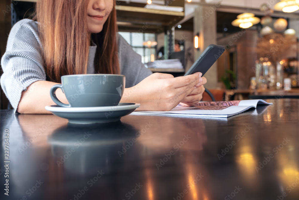 Closeup image of a woman holding and using a smart phone with coffee cup on table Closeup image of a woman holding and using a smart phone with coffee cup on table
