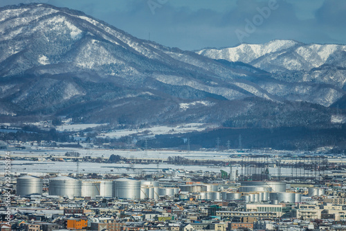 view of city; chemical tank plant and snow mountains in the winter