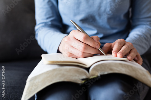 Bible Study - Woman Taking Notes as She Reads from an Open Bible photo