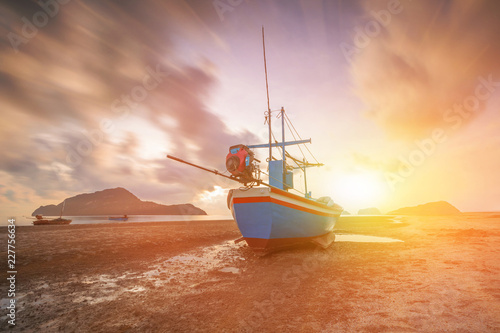 Fishing boat, waves clouds and orange sky at sunset, nature background.