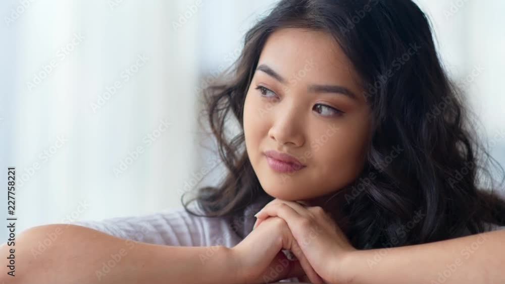 Close-up portrait modest dreaming smiling Asian woman leaning head on hands Close-up portrait modest dreaming smiling Asian woman leaning head on hands