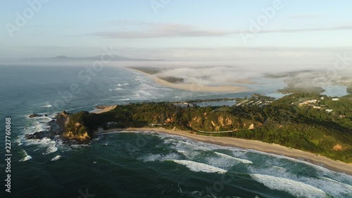 Headland cliffs of Nambucca Heads tipping towards Pacific ocean hiding delta of Nambucca river entering open sea at remote regional town in Australia.
 photo