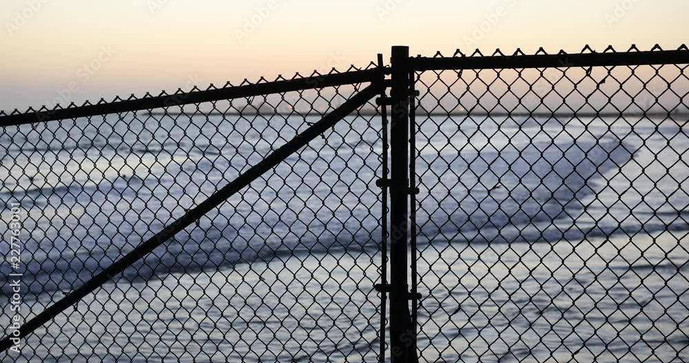 Background plate of Silhouetted chain-link fence in front of a California beach Background plate of Silhouetted chain-link fence in front of a California beach