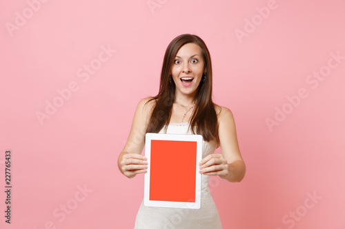 Portrait of excited bride woman in wedding dress hold tablet pc computer with blank black empty screen isolated on pastel pink background. Wedding to do list. Organization of celebration. Copy space.