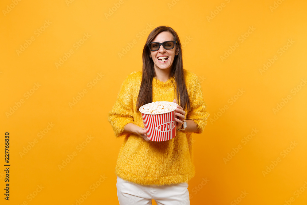 Portrait of laughing young girl in 3d imax glasses watching movie film, eat popcorn from bucket isolated on bright yellow background. People sincere emotions in cinema, lifestyle concept. Copy space. Portrait of laughing young girl in 3d imax glasses watching movie film, eat popcorn from bucket isolated on bright yellow background. People sincere emotions in cinema, lifestyle concept. Copy space.