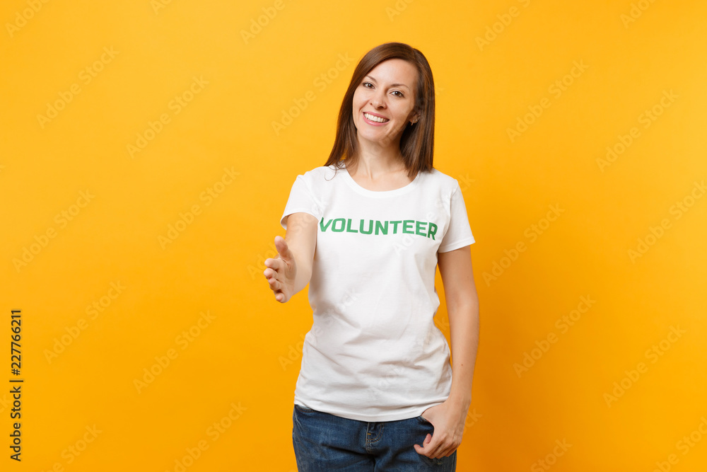 Portrait of happy smiling satisfied woman in white t-shirt with written inscription green title volunteer isolated on yellow background. Voluntary free assistance help, charity grace work concept. Portrait of happy smiling satisfied woman in white t-shirt with written inscription green title volunteer isolated on yellow background. Voluntary free assistance help, charity grace work concept.