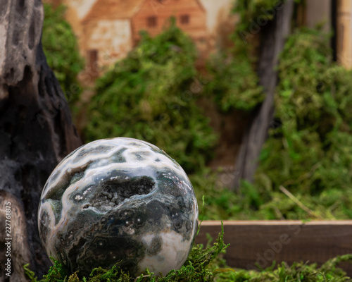 Orbicular ocean jasper sphere with crystallized vugs from Madagascar on moss, bryophyta and wooden background