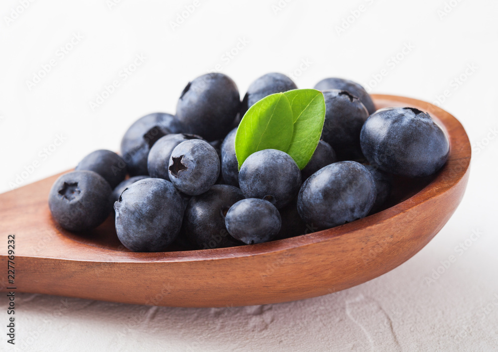 Fresh raw organic blueberries with leaf on wooden spoon on white background. Food concept. Fresh raw organic blueberries with leaf on wooden spoon on white background. Food concept.