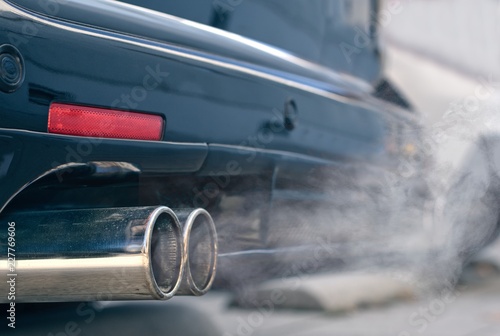 Close up of smoky dual exhaust pipes from a starting diesel car. photo
