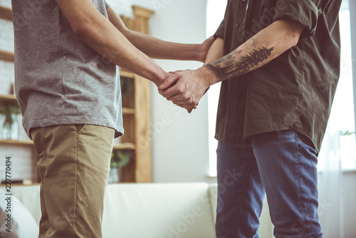 Tender touch. Cropped close up portrait of young man with tattoo holding arm of boyfriend