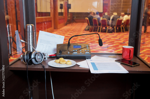 Translator room . translators cubicle . interpreting - Microphone and switchboard in an simultaneous interpreter booth . Soft focus of wireless Conference microphones and notebook in a meeting room.