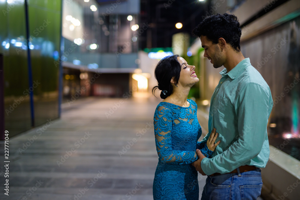 Young Hispanic couple exploring the city streets at night togeth Young Hispanic couple exploring the city streets at night togeth