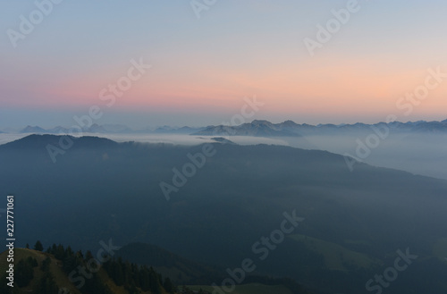 Mystical pastel-coloured alpine landscape after sunset with rocky mountains above clouds and mist. View from the summit of the Gruenten mountain (Allgaeu Alps, Bavaria, Germany).