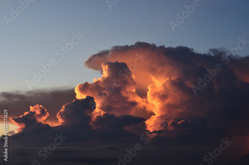 Cumulonimbus cloud formations on tropical sky with horizon is turning yellow at sunset , Nimbus moving , Purple and orange color clouds hunk at night , Thailand 