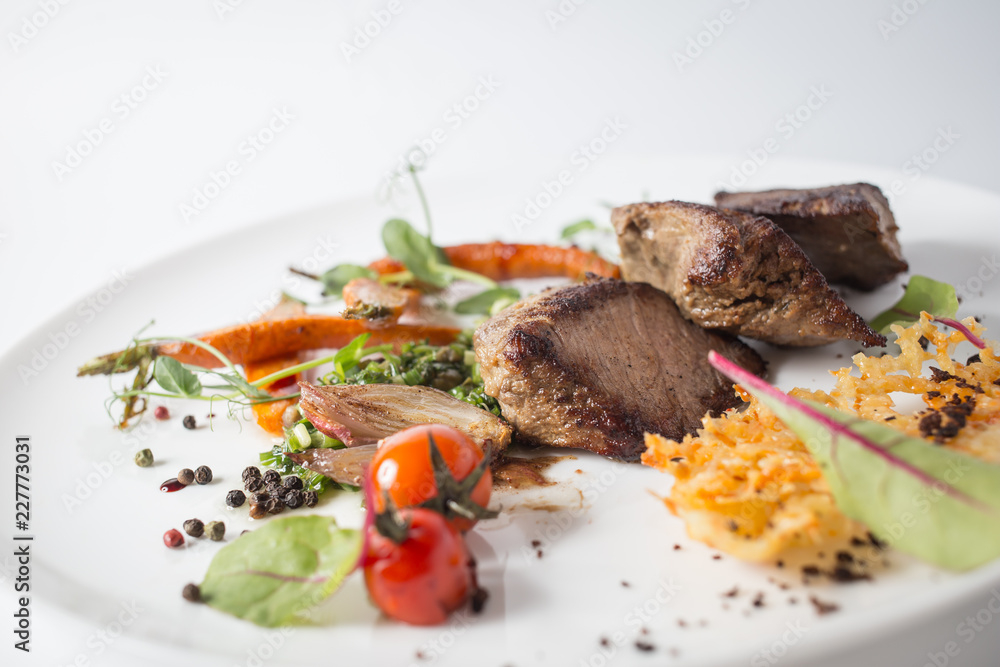 Baked meat with cheese, carrot, onion, green and tomatoes on white plate Baked meat with cheese, carrot, onion, green and tomatoes on white plate