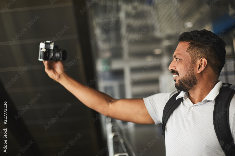 Cheerful handsome hindu man using his camera while making selfies