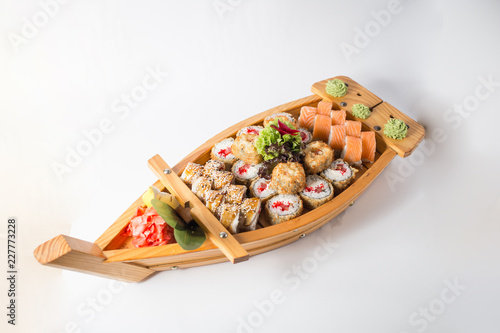 Wooden boat with lots of sushi with ginger and wasabi