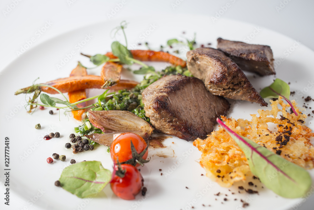 Baked meat with cheese, carrot, onion, green and tomatoes on white plate Baked meat with cheese, carrot, onion, green and tomatoes on white plate