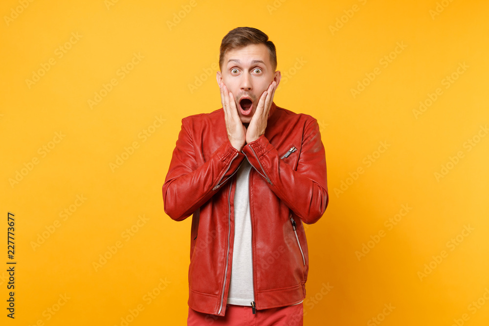 Portrait vogue shocked handsome young man 25-30 years in red leather jacket, t-shirt standing isolated on bright trending yellow background. People sincere emotions lifestyle concept. Advertising area Portrait vogue shocked handsome young man 25-30 years in red leather jacket, t-shirt standing isolated on bright trending yellow background. People sincere emotions lifestyle concept. Advertising area