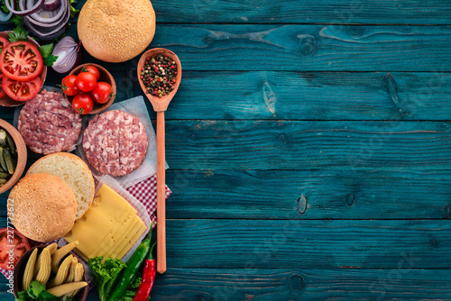 Preparation of burger. Meat, tomatoes, onions. On a blue wooden background. Top view. Free copy space.