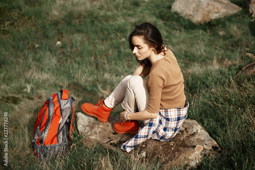 Top view of calm lady sitting and relaxing on stone. She hiking with rucksack through rocky countryside