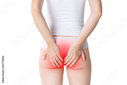 Woman suffering from hemorrhoids, anal pain on gray background